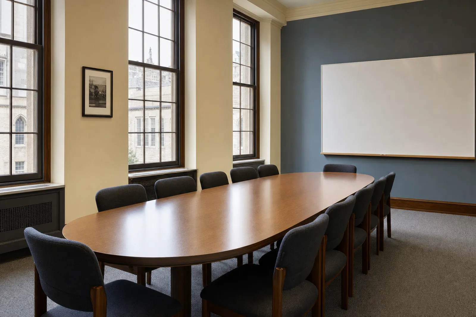 An empty university seminar room with an oval table and tall windows